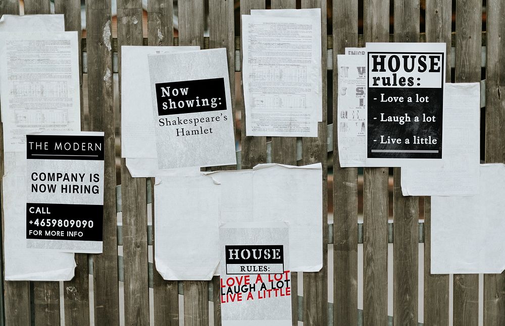 Sheets of paper ads on a wooden fence