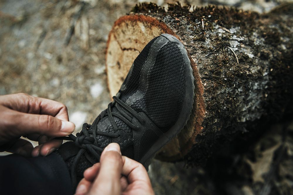 Man tieing his shoelaces on a tree stump
