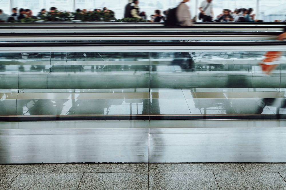 People on a moving walkway in a passenger terminal at the airport