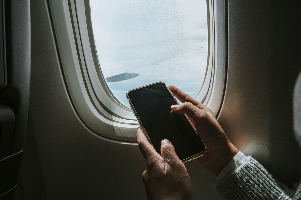 Woman using her phone by a plane window