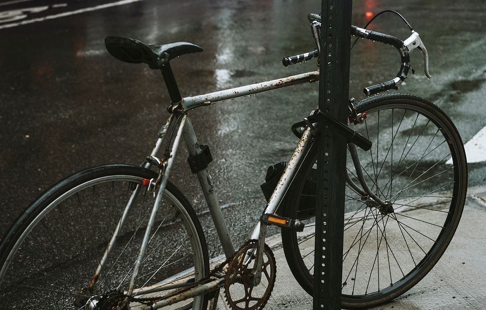 Rustic bicycle locked with a rack on a wet streetside