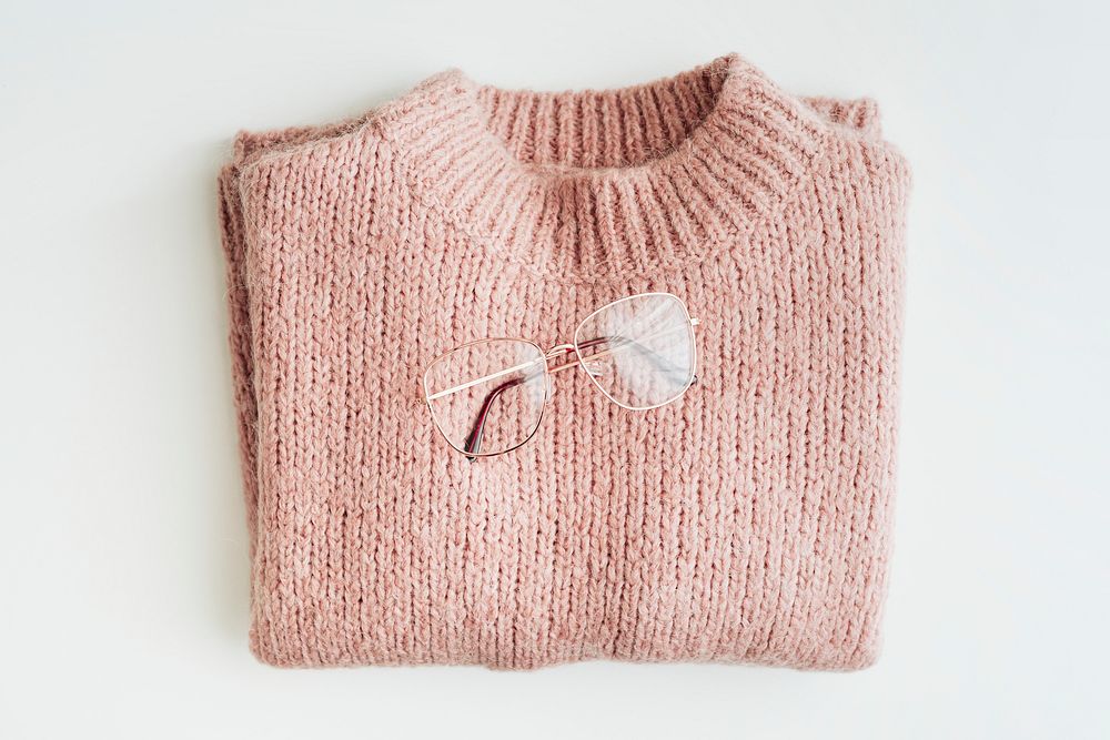 Flat lay of glasses on a pink knitted sweater