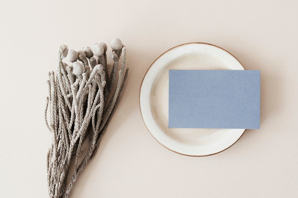 Blank blue business card on a plate with dried plant