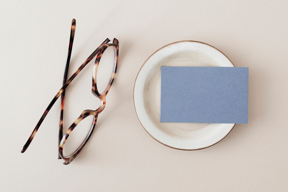 Blank blue business card on a plate with glasses
