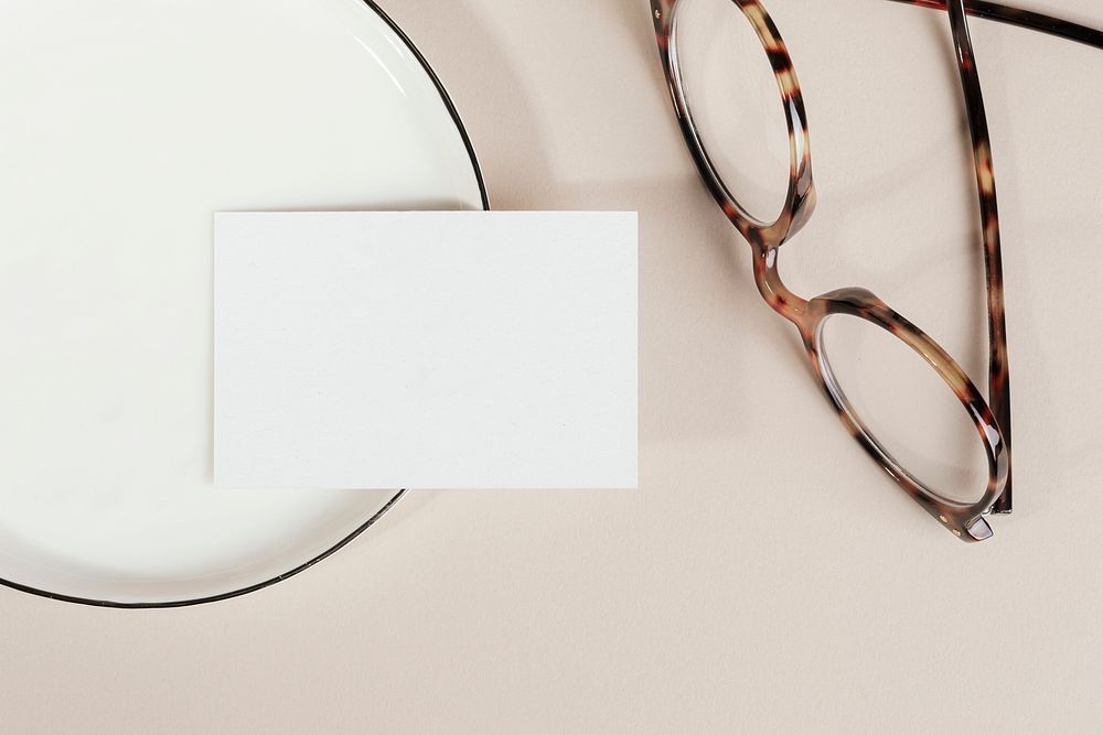 Blank business card on a plate with glasses