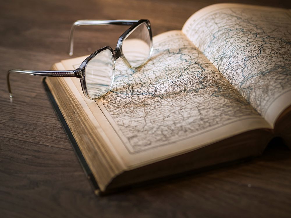 Free glasses on open book of map photo, public domain CC0 image.