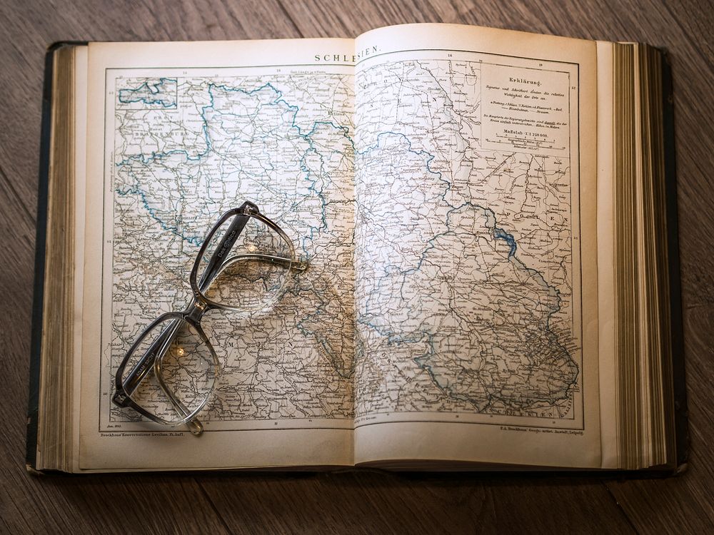 Free glasses on open book of map photo, public domain CC0 image.