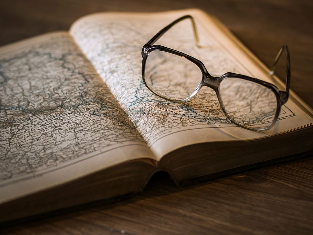 Free glasses on open book of map photo, public domain CC0 image.