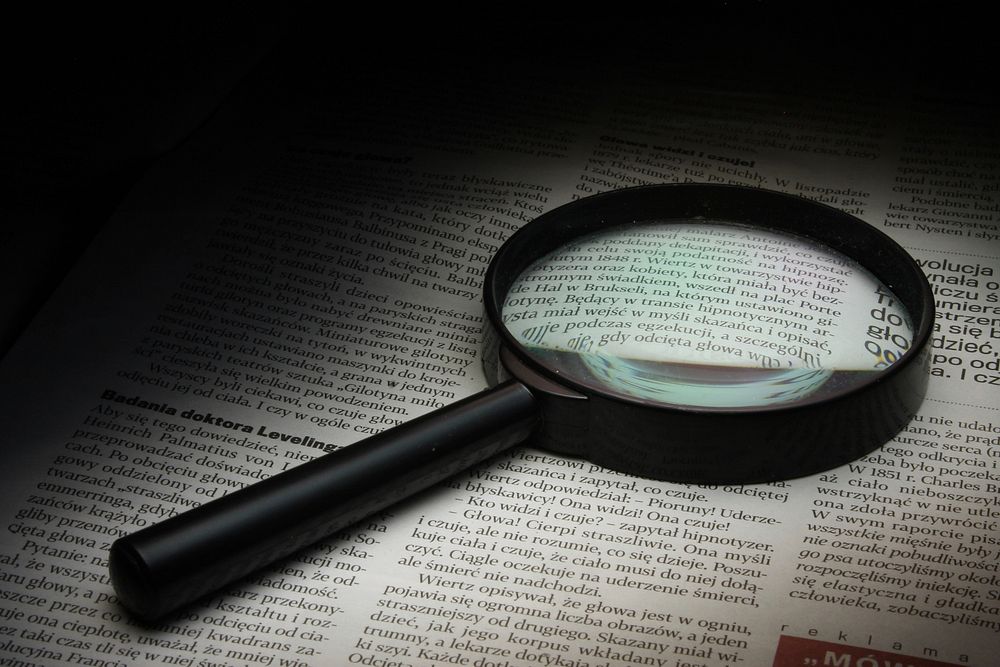 Free magnifying glass on newspaper photo, public domain tool CC0 image.