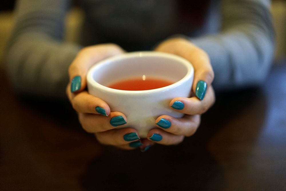 Free woman grabbing coffee cup top view photo, public domain beverage CC0 image.