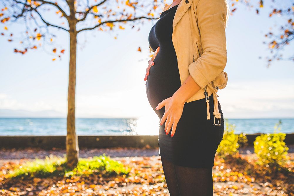 Pregnant woman standing with beach background 