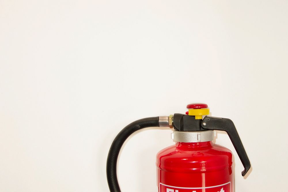 Free fire extinguisher on white wall photo, public domain emergency CC0 image.