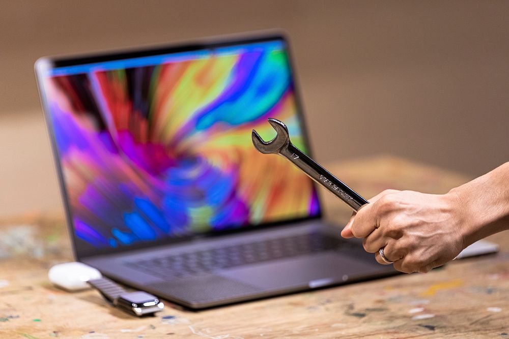 Free hand holding wrench in front of laptop image, public domain CC0 photo.