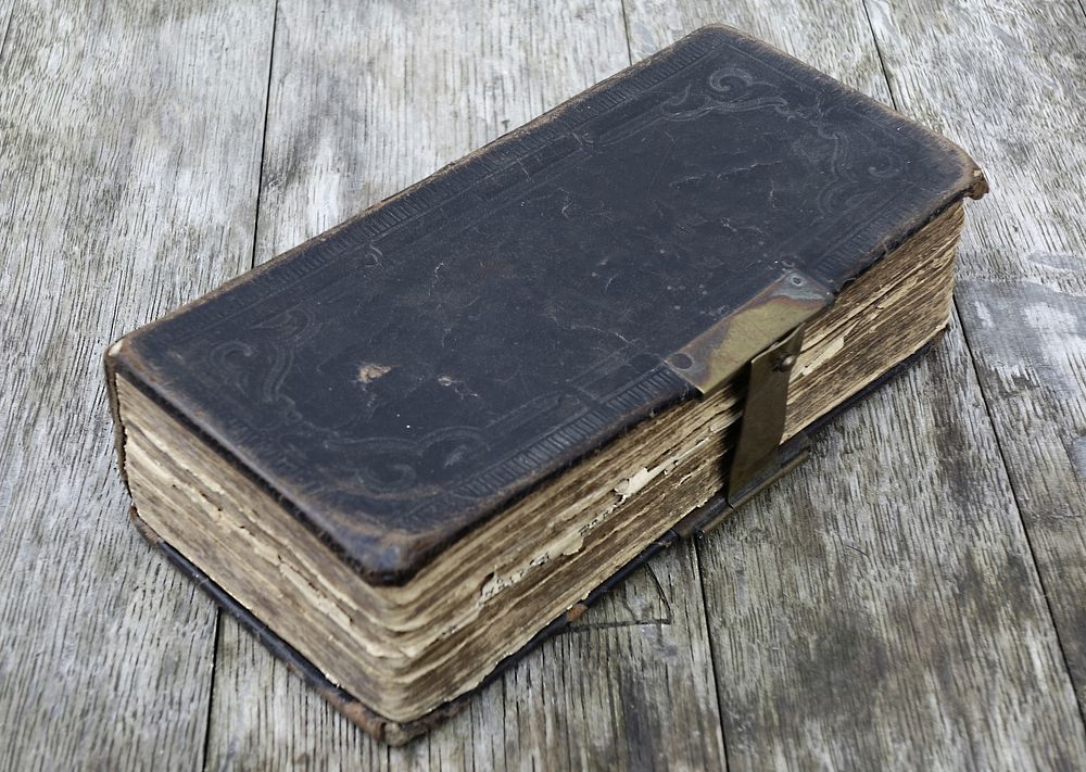 Free old closed book on wooden table photo, public domain CC0 image.