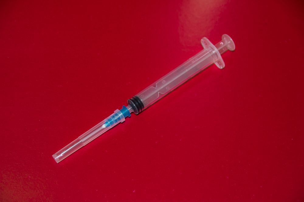 Free syringe on red background photo, public domain medical CC0 image.