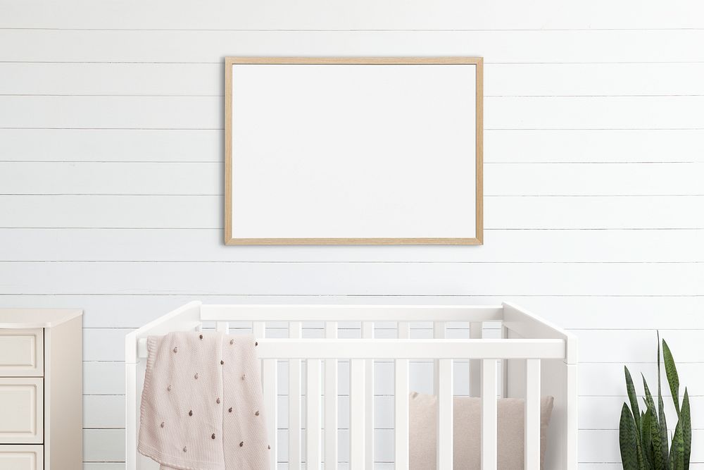 Blank picture frames hanging above a crib in a minimal nursery room