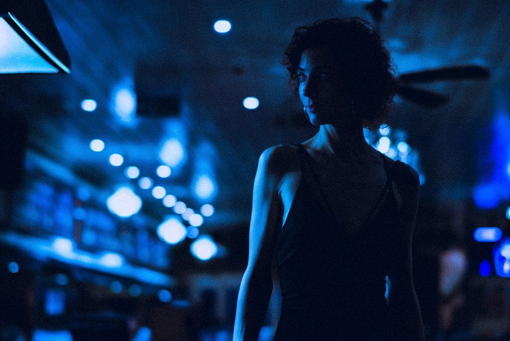 Blue neon woman portrait, standing in a bar, nightlife aesthetic