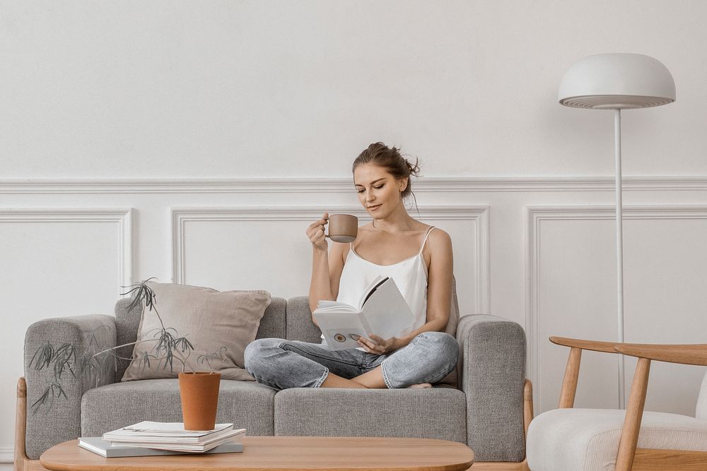 Woman reading while having tea in the living room, hobby photo