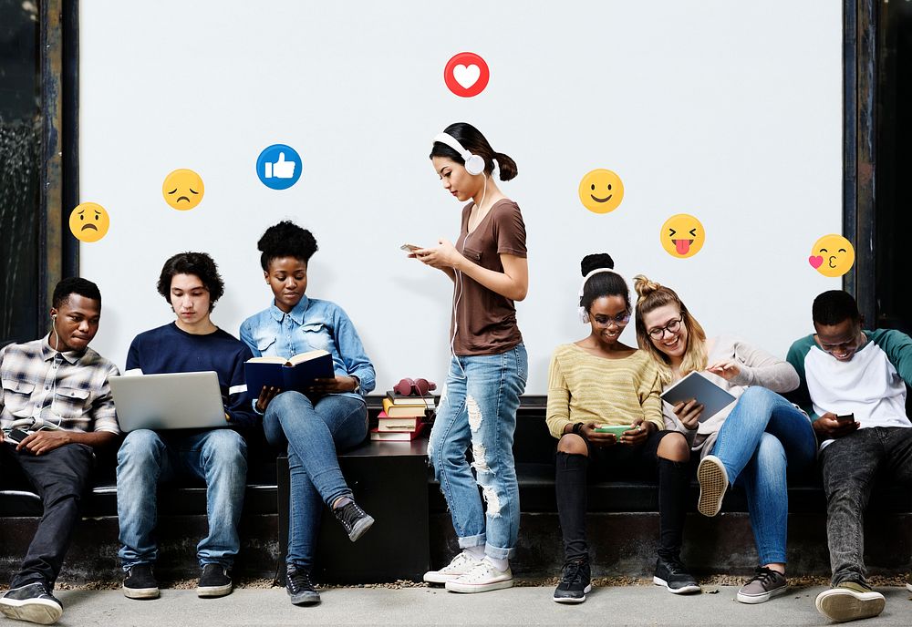 Cheerful students with emoticons using digital devices