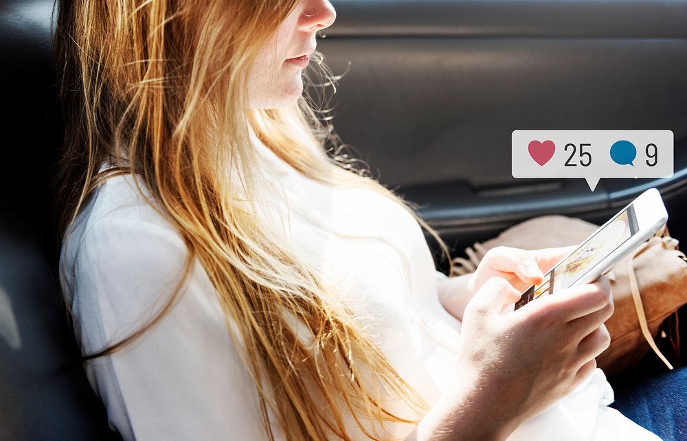 Young woman using social media on her smartphone while in a car