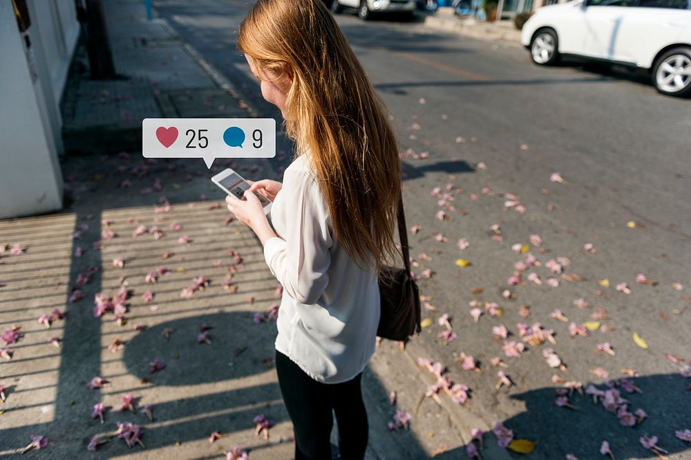 Young woman using social media on her smartphone while walking the streets