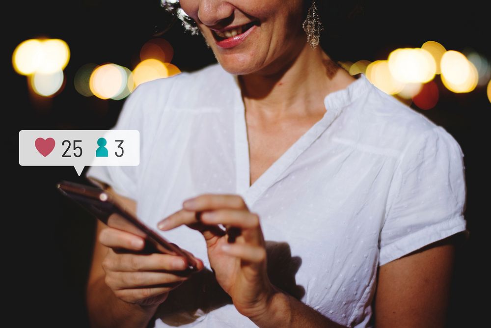 Happy adult woman using her smartphone at a dinner party