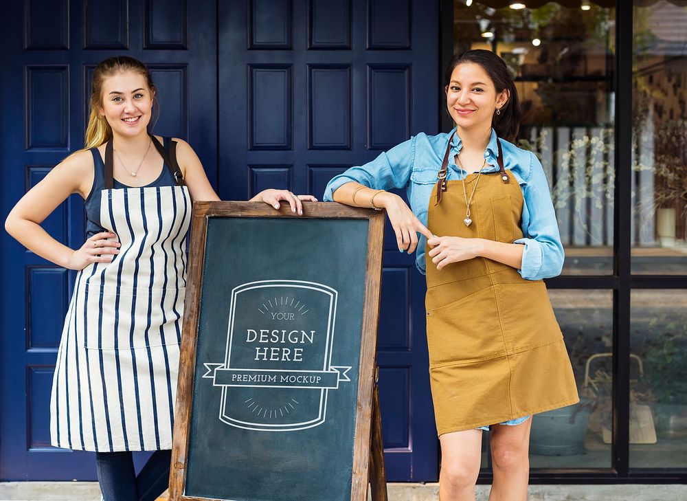 Cheerful business owners standing with blackboard mockup