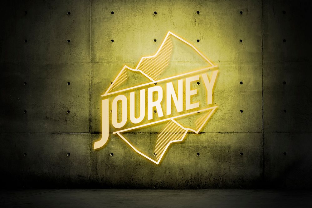 Neon yellow journey sign with mountains on a wall