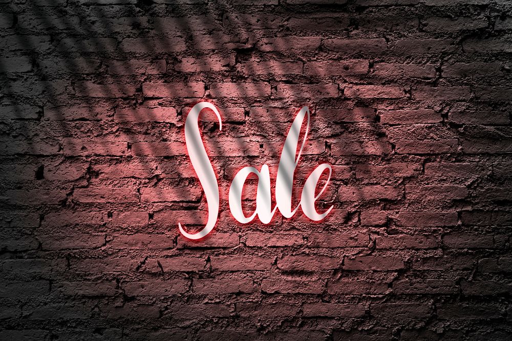 Neon red sale sign on a brick wall
