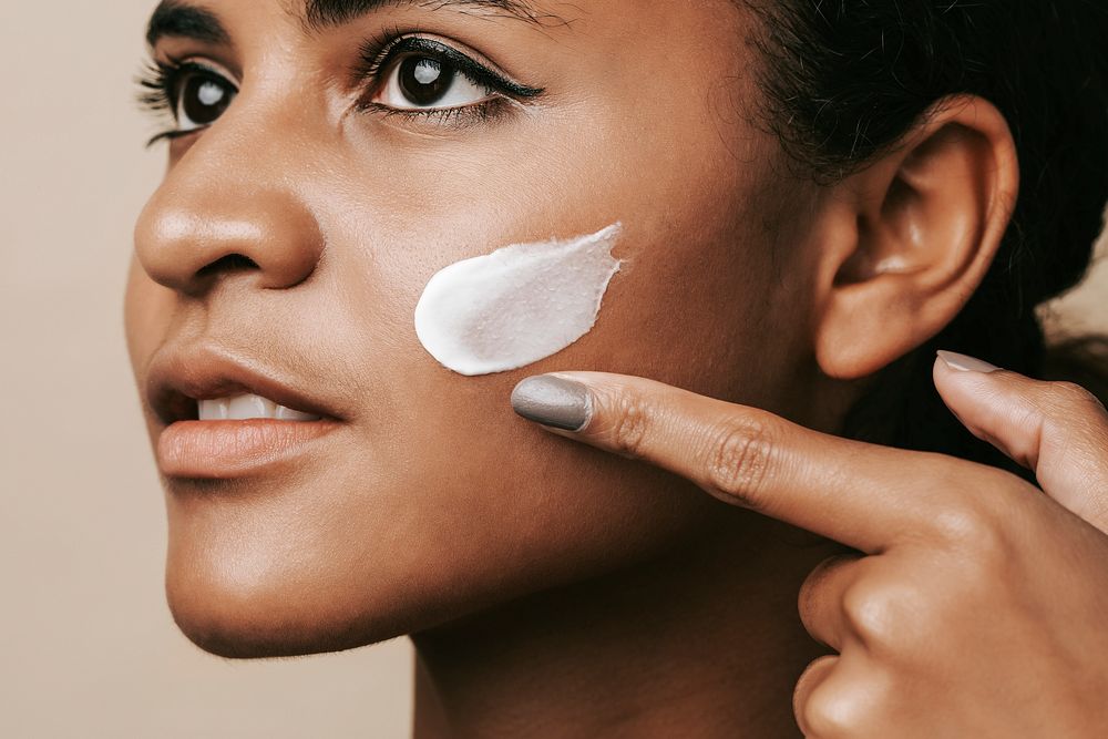 Beautiful woman applying moisturizing cream, skincare routine