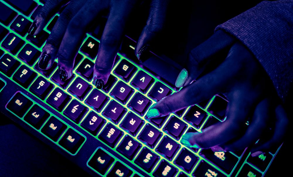 Woman typing on glowing keyboard at night