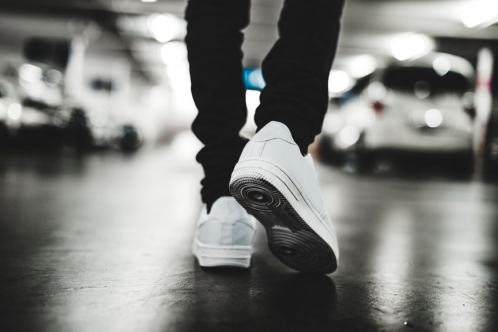 Man in white sneakers walking in parking lot