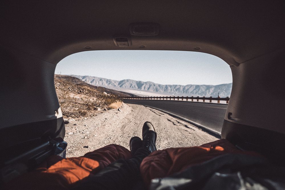 Man lying in his car while resting from a road trip