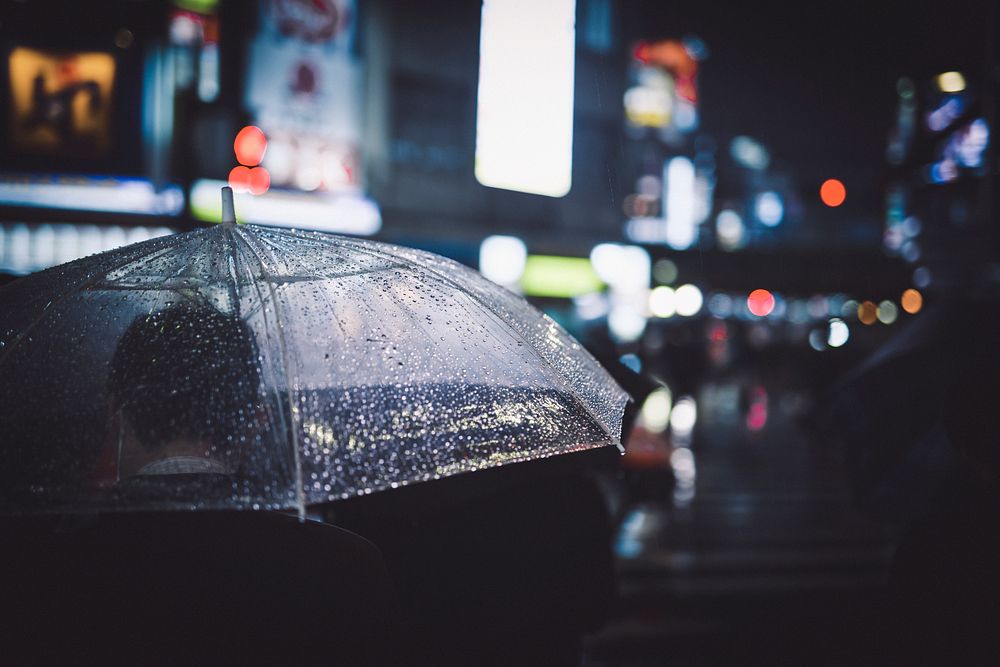 Man walking with umbrella in a city on rainy night