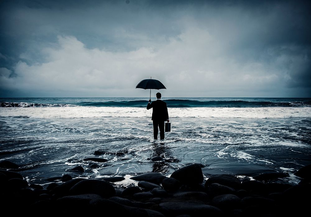 Businessman with umbrella in ocean, business risk