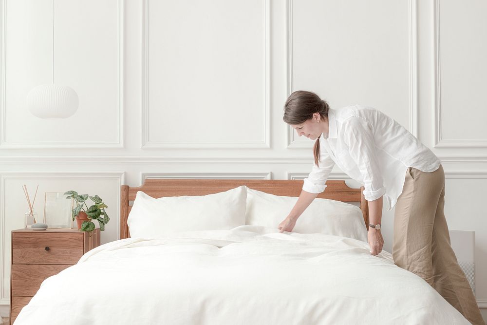 Woman making her bed, Scandinavian interior bedroom