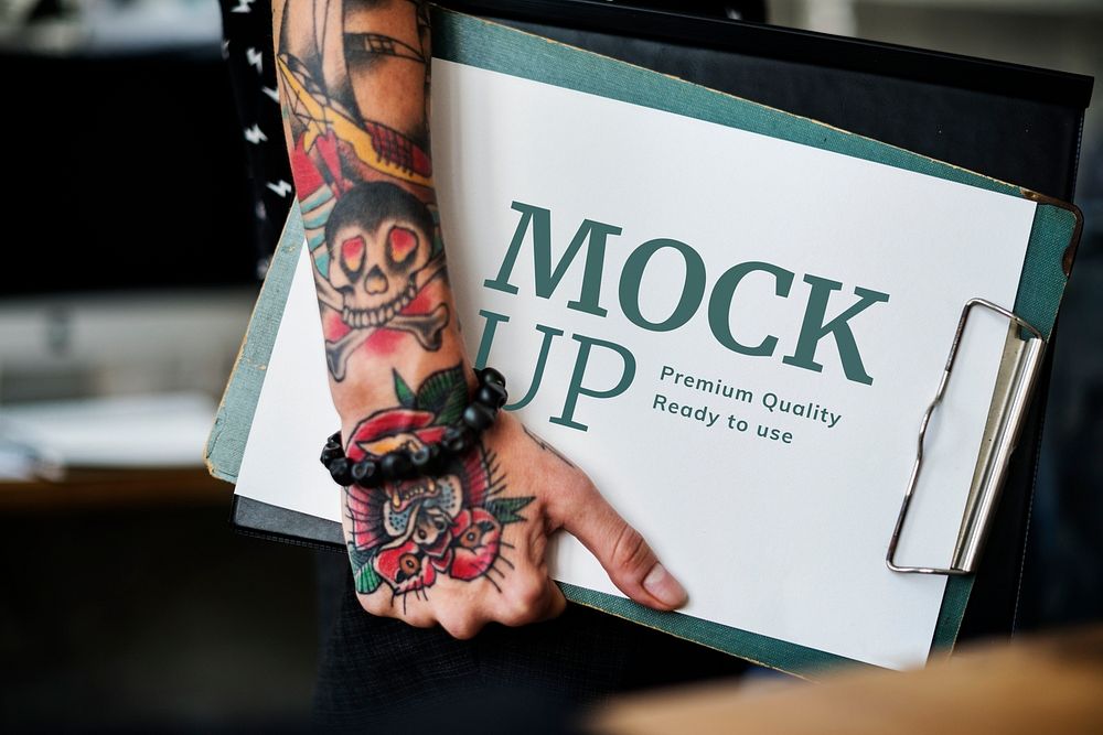 Tattooed woman holding a paper mockup on a clipboard
