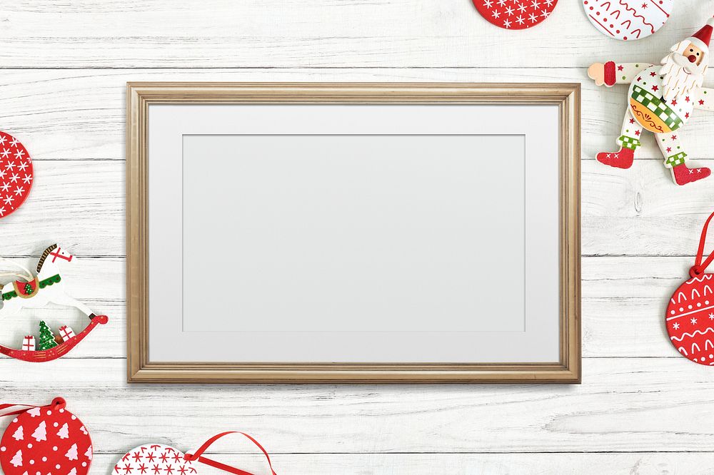 Classic gold frame mockup with Christmas decorations on white wooden background