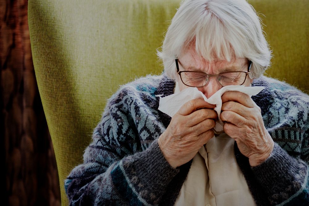 Senior woman sneezing and showing covid-19 symptoms