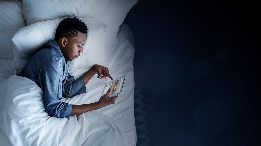 Man using a tablet in bed at night