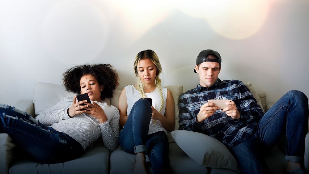 Diverse young people texting on a couch
