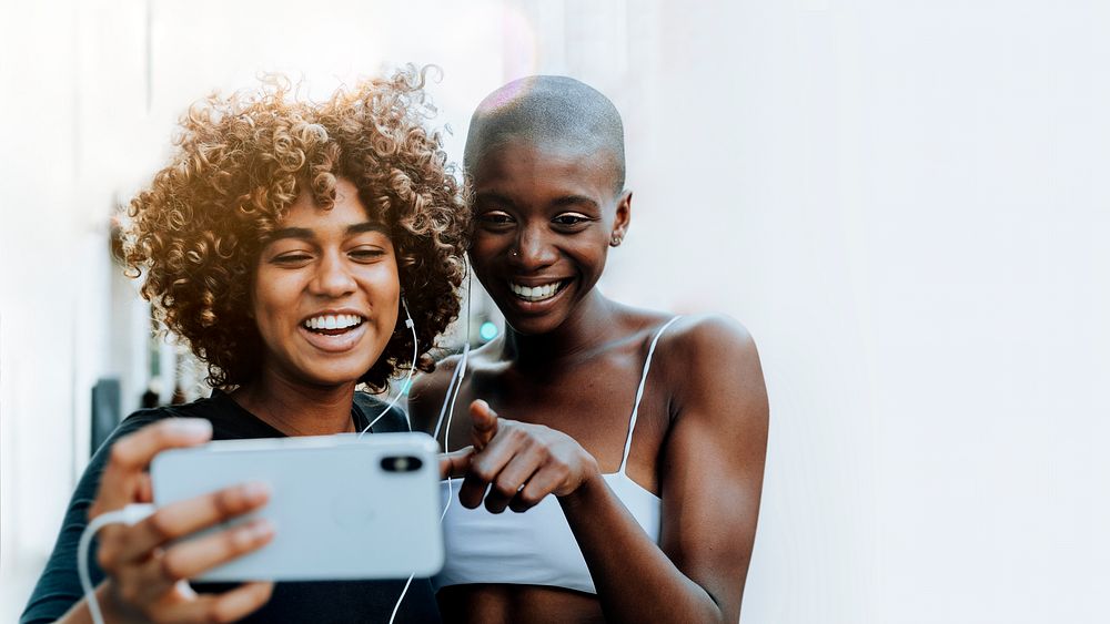 Black women laughing at a phone screen