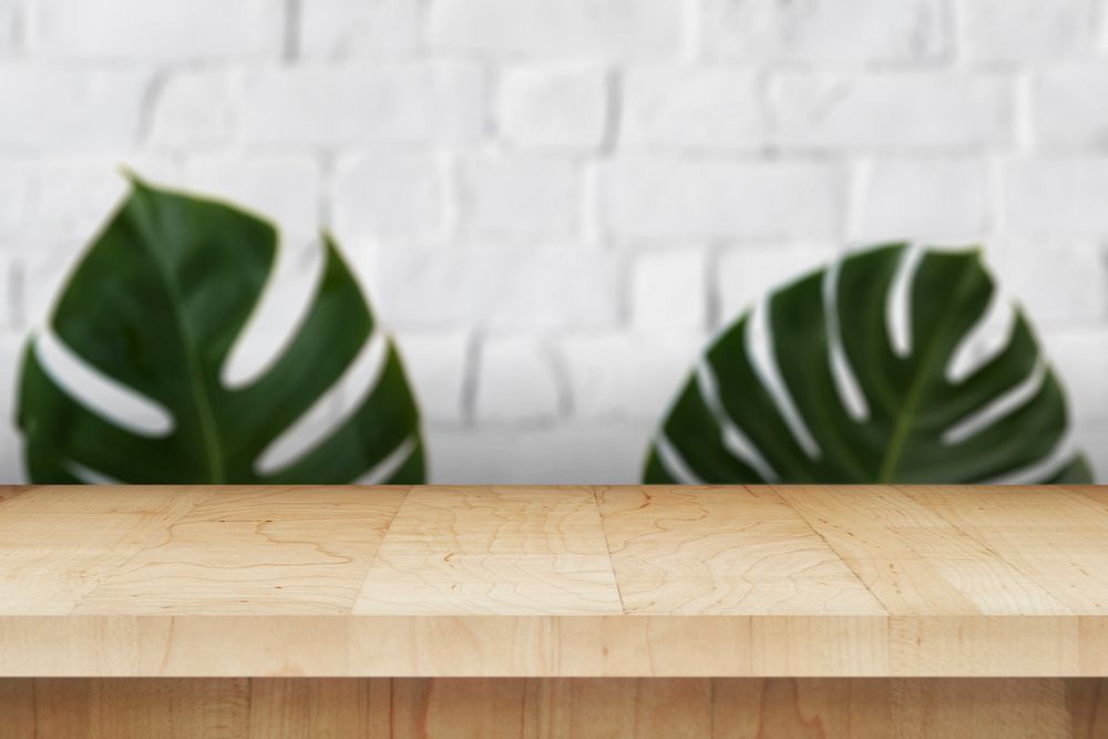 Wooden table with leaves on a white brick wall product background