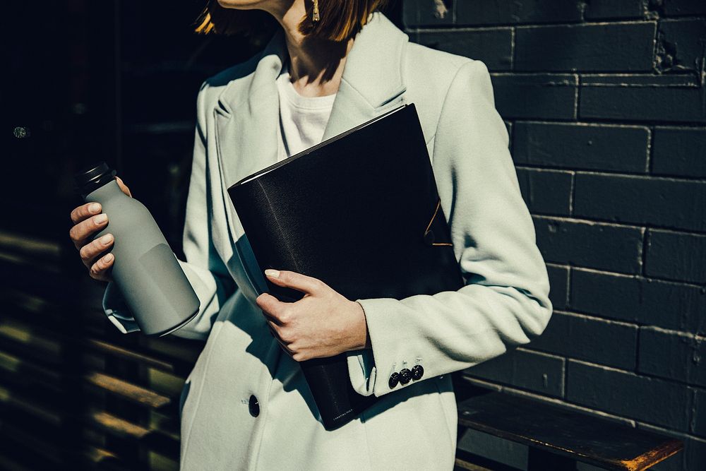 Businesswoman with gray bottle and black folders