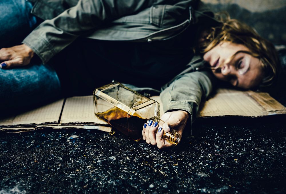Drunk homeless woman sleeping on a dirty street