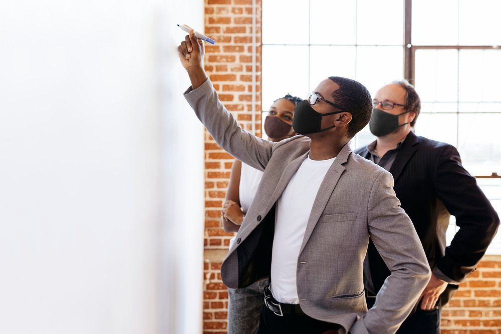 Business people wearing masks brainstorming on a whiteboard, the new normal