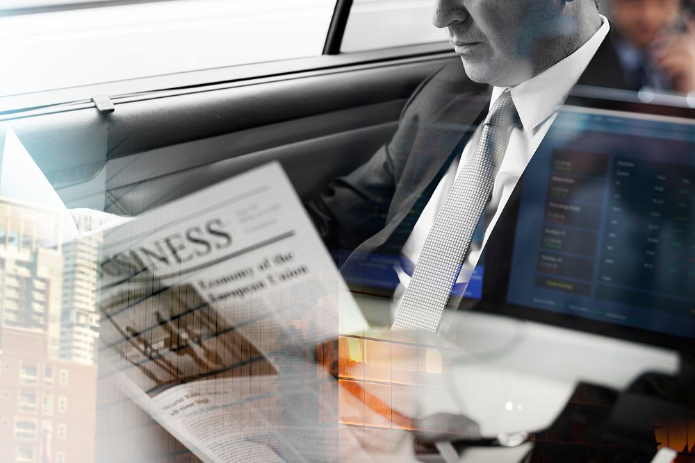 Businessman reading newspaper in car with city background overlay