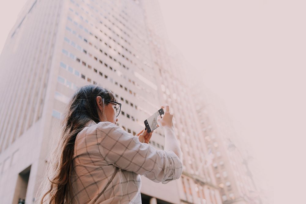 Woman using smartphone taking a picture in city