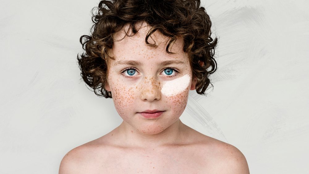 Curly haired boy with freckles and white paint on his cheek wallpaper