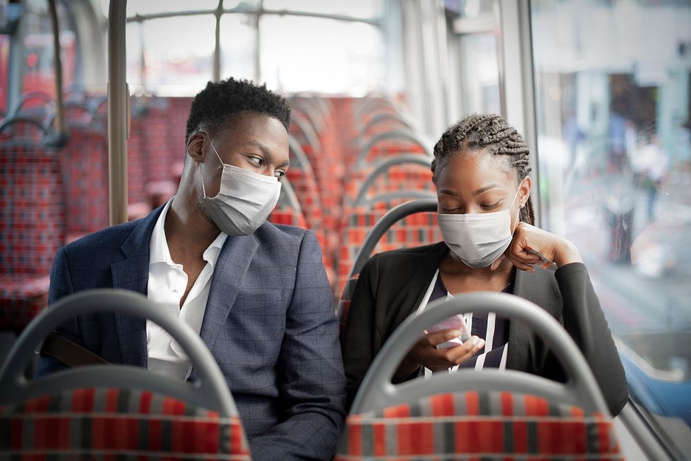 Business couple wearing mask on the bus while traveling on public transportation in the new normal